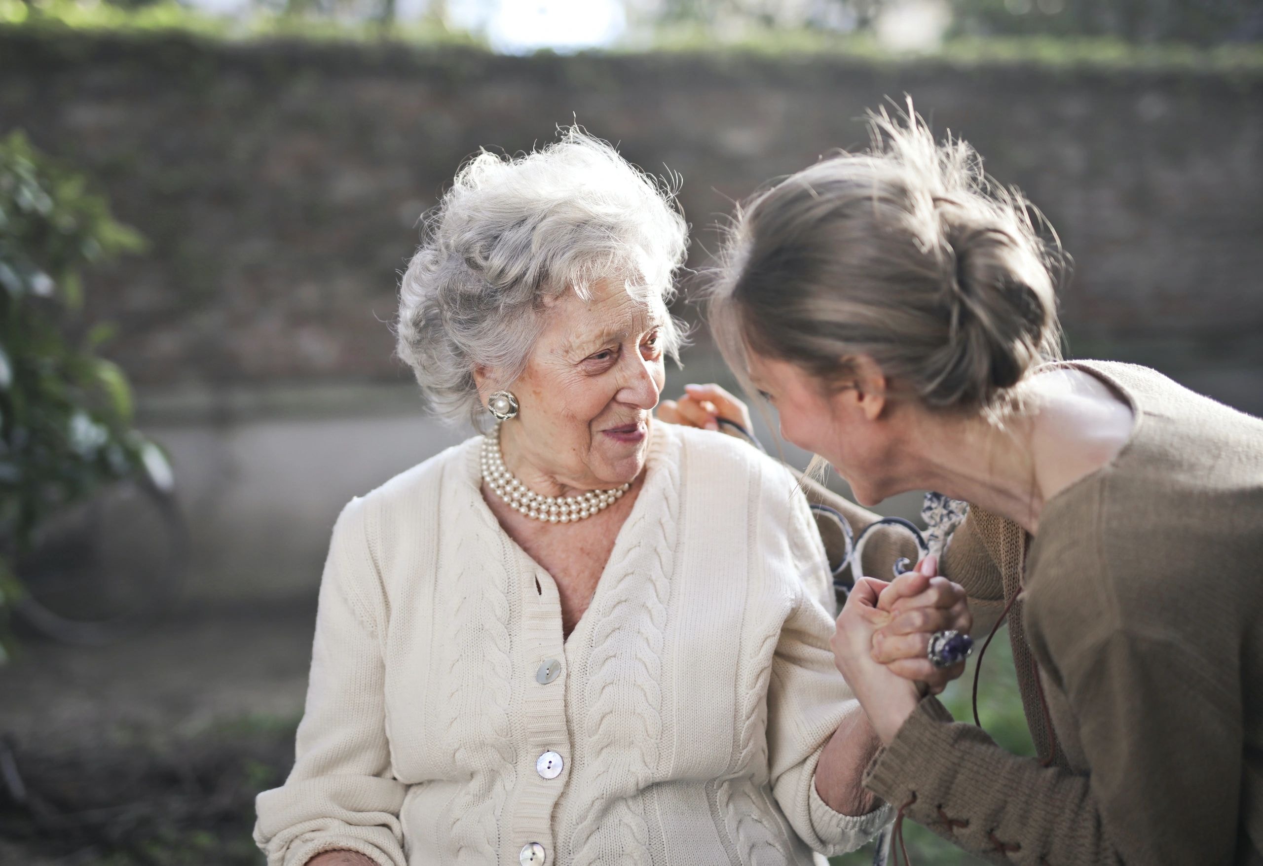 Two women in conversation outdoors — caregiver and senior